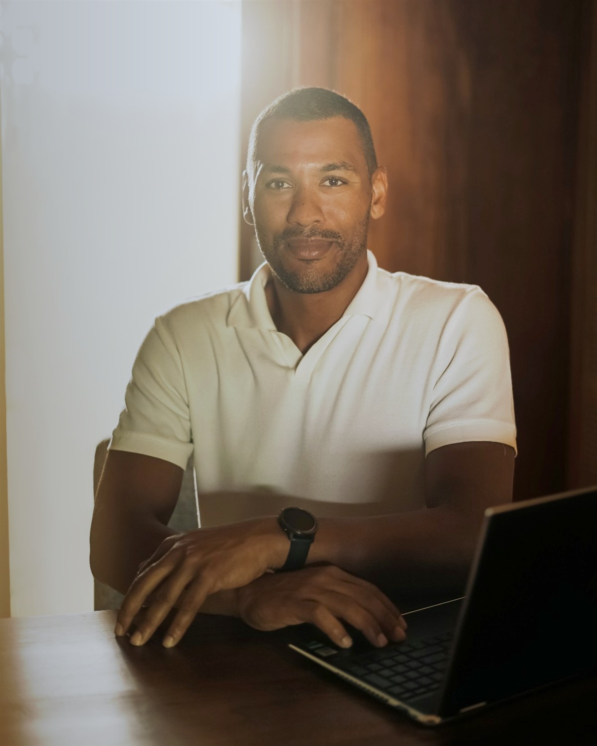 Portrait of Mwata Belgrave seated at a desk with a laptop